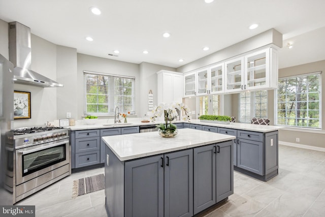 kitchen with wall chimney exhaust hood, kitchen peninsula, appliances with stainless steel finishes, and white cabinets