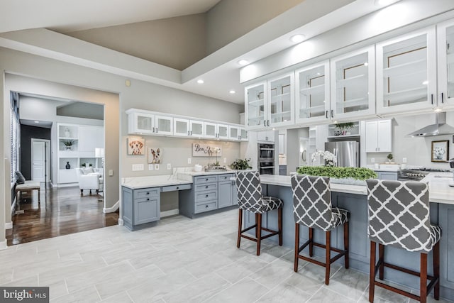 kitchen with high vaulted ceiling, appliances with stainless steel finishes, white cabinets, and a breakfast bar