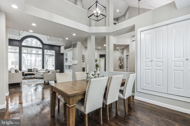 dining area with a notable chandelier, a high ceiling, and dark wood-type flooring