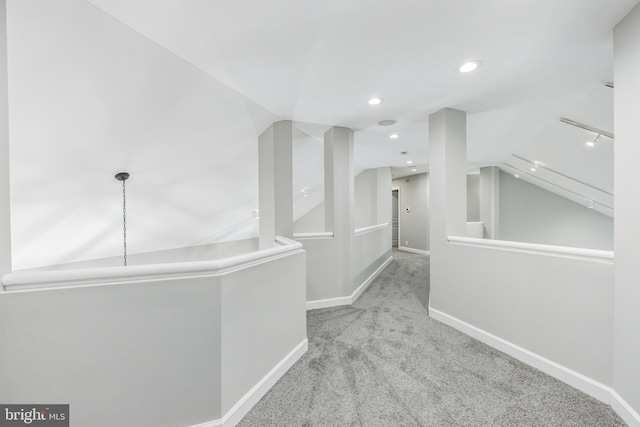 hallway with vaulted ceiling and light carpet