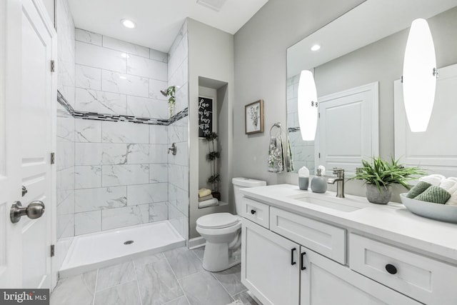 bathroom with tile flooring, vanity, a tile shower, and toilet