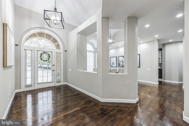 foyer entrance with an inviting chandelier, dark wood-type flooring, and lofted ceiling