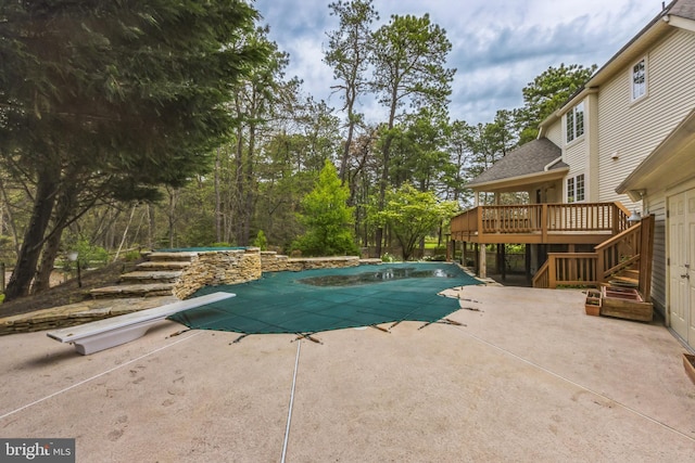 view of pool with a patio, a diving board, and a wooden deck