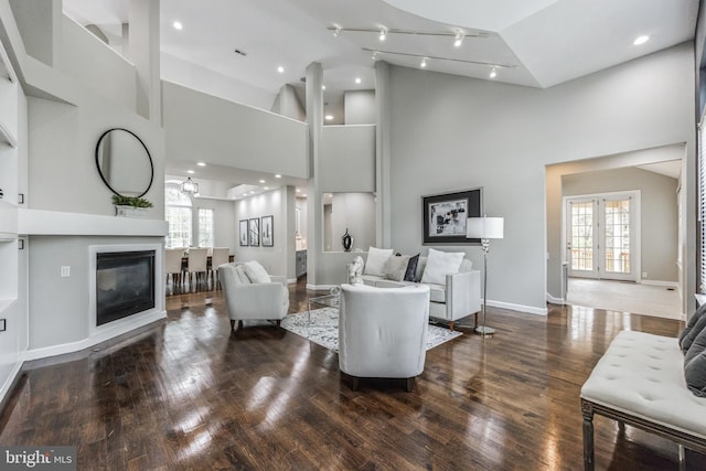 living room featuring wood-type flooring, french doors, and a towering ceiling