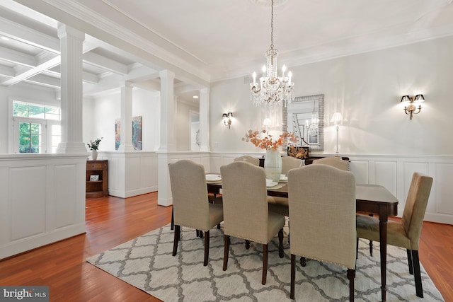 dining space featuring ornate columns, a notable chandelier, crown molding, and light wood-type flooring