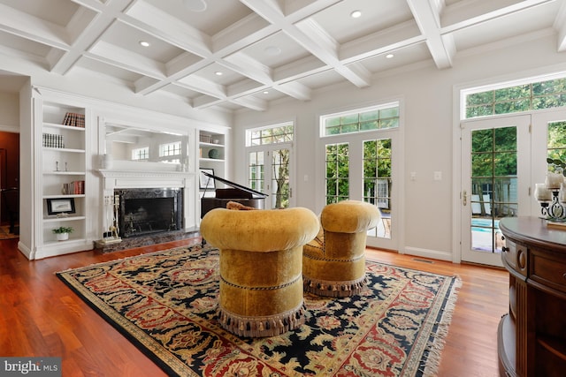 living room with beamed ceiling, a fireplace, coffered ceiling, french doors, and hardwood / wood-style flooring