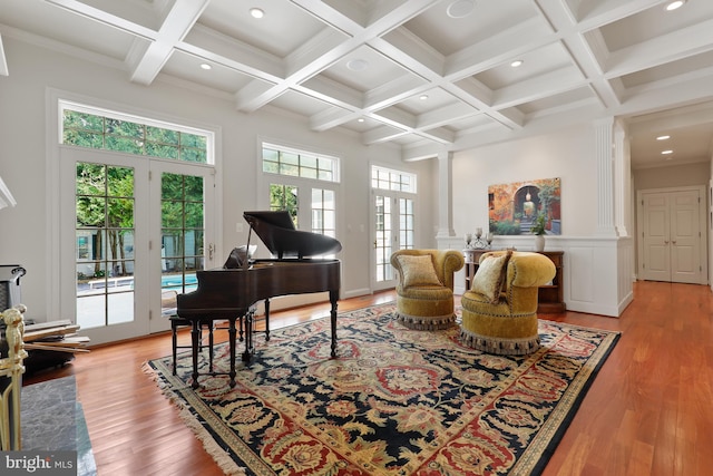 living room featuring beamed ceiling, a towering ceiling, coffered ceiling, light hardwood / wood-style floors, and french doors