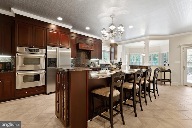 kitchen featuring a center island, decorative light fixtures, light tile flooring, crown molding, and appliances with stainless steel finishes