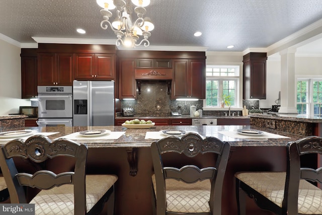 kitchen with ornamental molding, a notable chandelier, decorative light fixtures, and stainless steel appliances