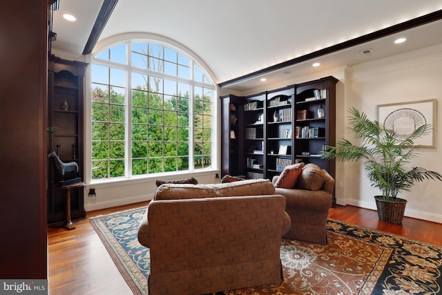 living room featuring wood-type flooring, crown molding, and vaulted ceiling with beams