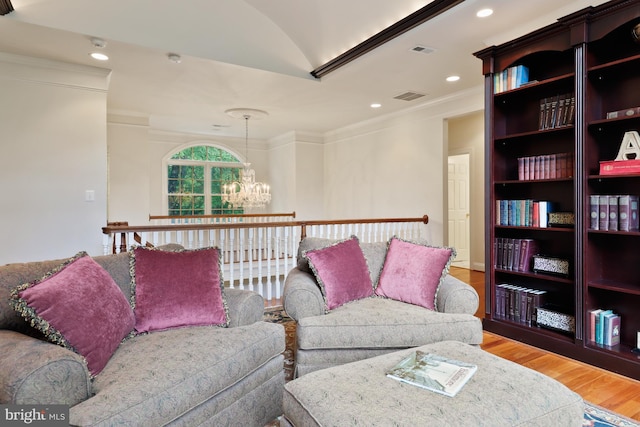 living room with ornamental molding, wood-type flooring, and a notable chandelier