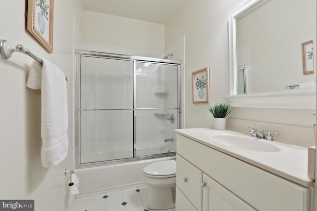 full bathroom with tile flooring, oversized vanity, toilet, and bath / shower combo with glass door