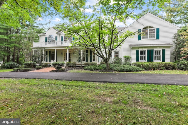 view of front property with a porch, a balcony, and a front yard