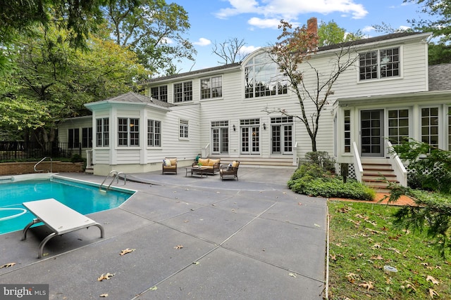 rear view of house with a fenced in pool and a patio area