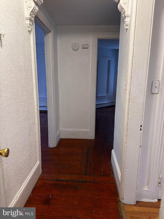 corridor featuring a baseboard heating unit and hardwood / wood-style flooring