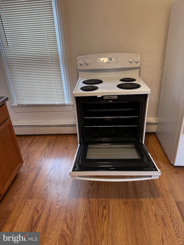 interior details featuring white appliances, a baseboard radiator, and light hardwood / wood-style flooring