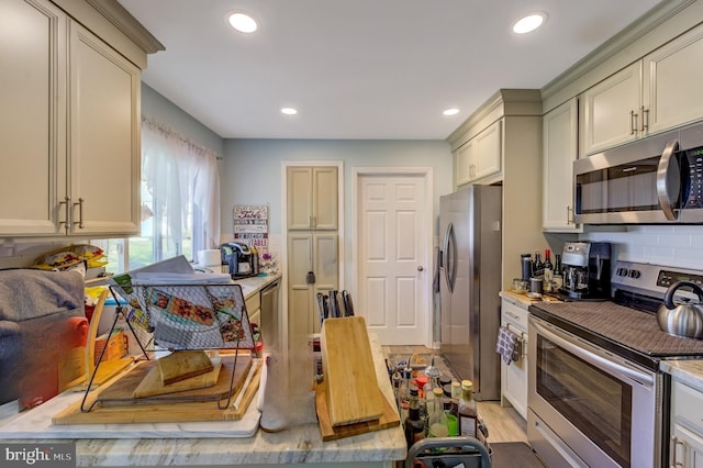 kitchen featuring cream cabinets, light hardwood / wood-style flooring, and stainless steel appliances