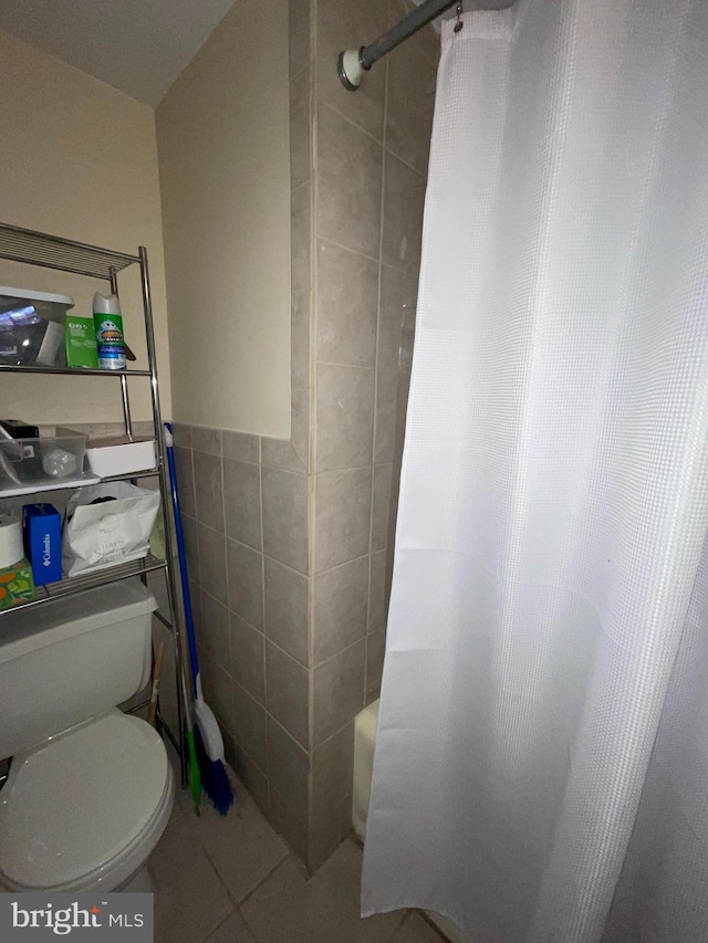 bathroom featuring tile patterned flooring, toilet, tile walls, and shower / tub combo