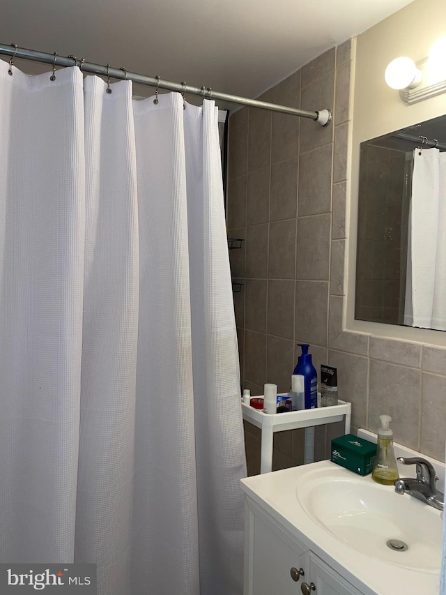 bathroom with vanity, tile walls, and tasteful backsplash