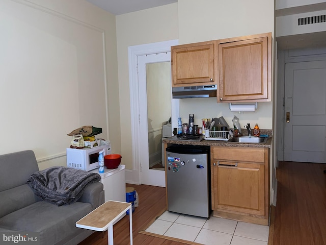 kitchen with refrigerator, light tile patterned flooring, and sink