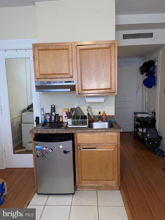 kitchen with light tile patterned flooring, sink, and fridge