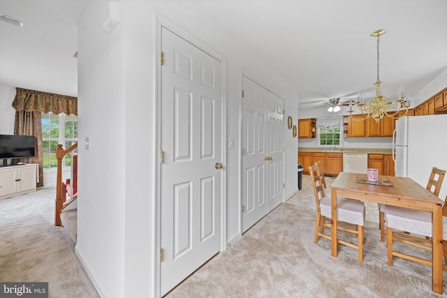 carpeted dining area with sink and ceiling fan with notable chandelier