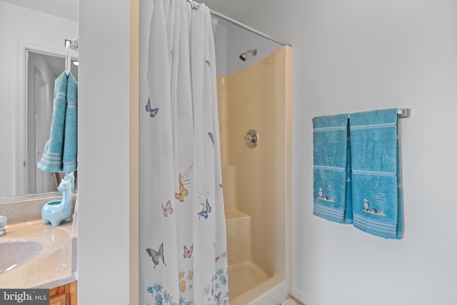 bathroom featuring a shower with shower curtain and vanity with extensive cabinet space