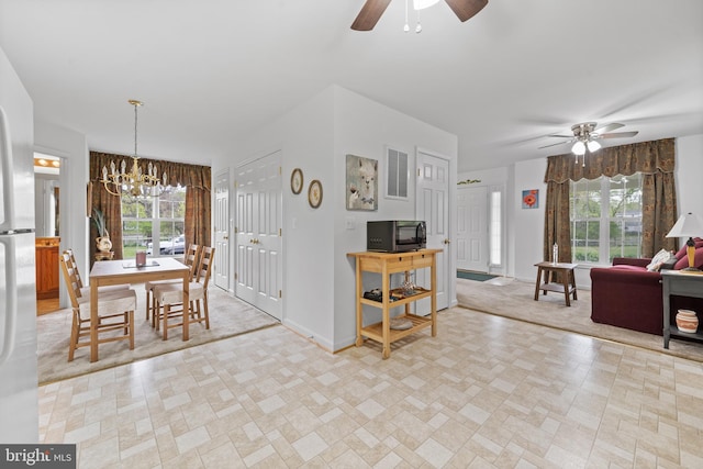 dining space with ceiling fan with notable chandelier and light tile floors