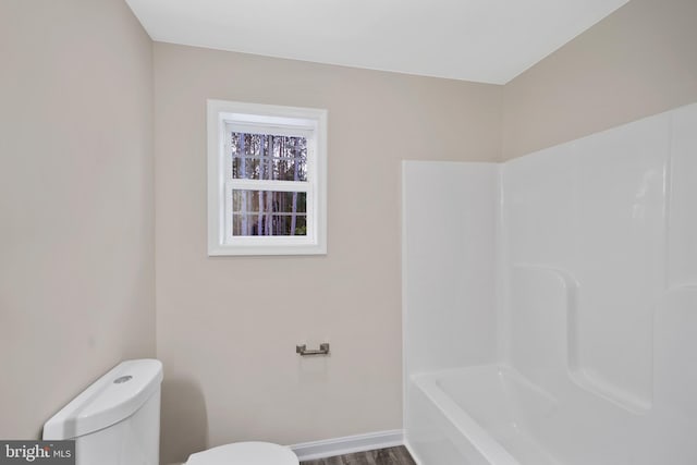 bathroom featuring wood-type flooring, toilet, and a bath