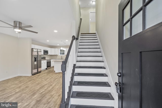 stairs featuring hardwood / wood-style flooring and ceiling fan