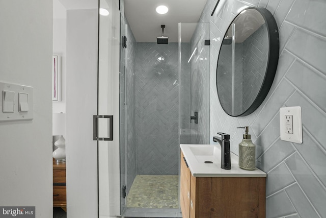 bathroom with walk in shower, vanity, tile floors, and tile walls