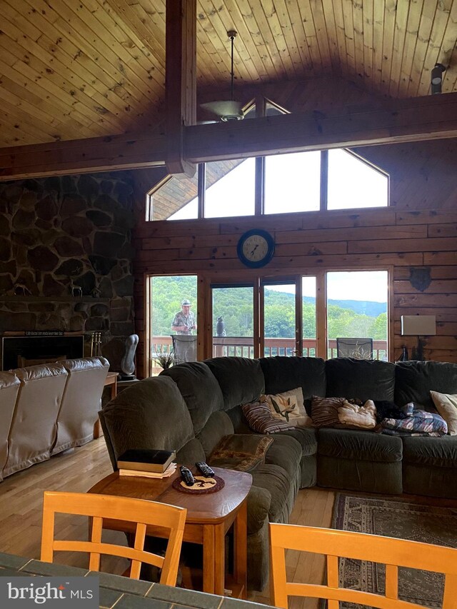 living room featuring vaulted ceiling with beams, wooden ceiling, light hardwood / wood-style floors, and a fireplace