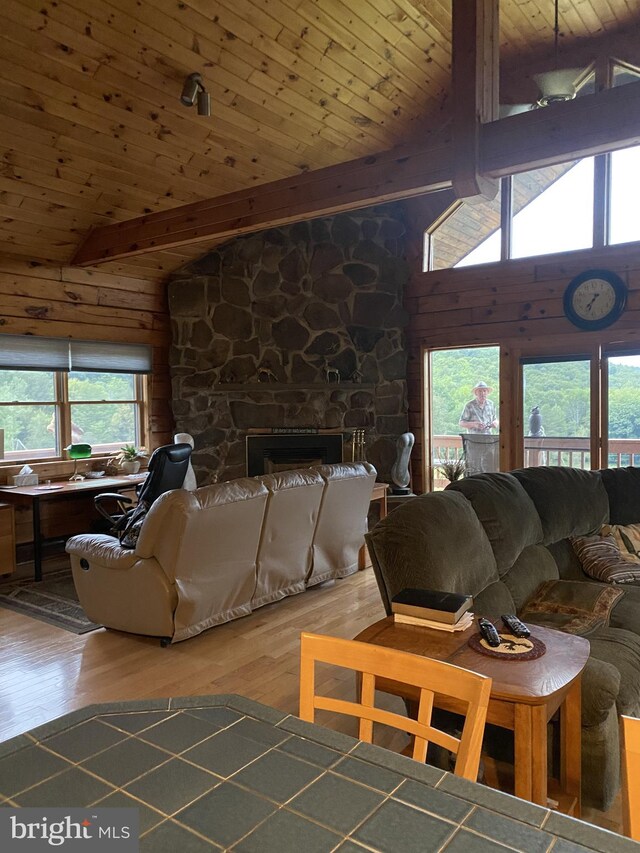 living room featuring a wealth of natural light, wood-type flooring, wooden walls, and beamed ceiling