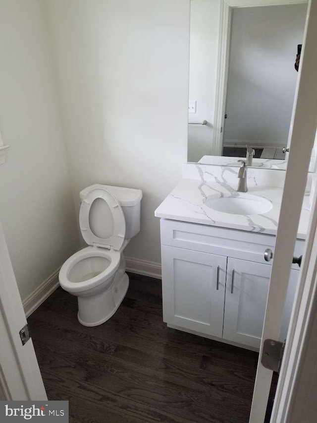 bathroom featuring toilet, wood-type flooring, and vanity