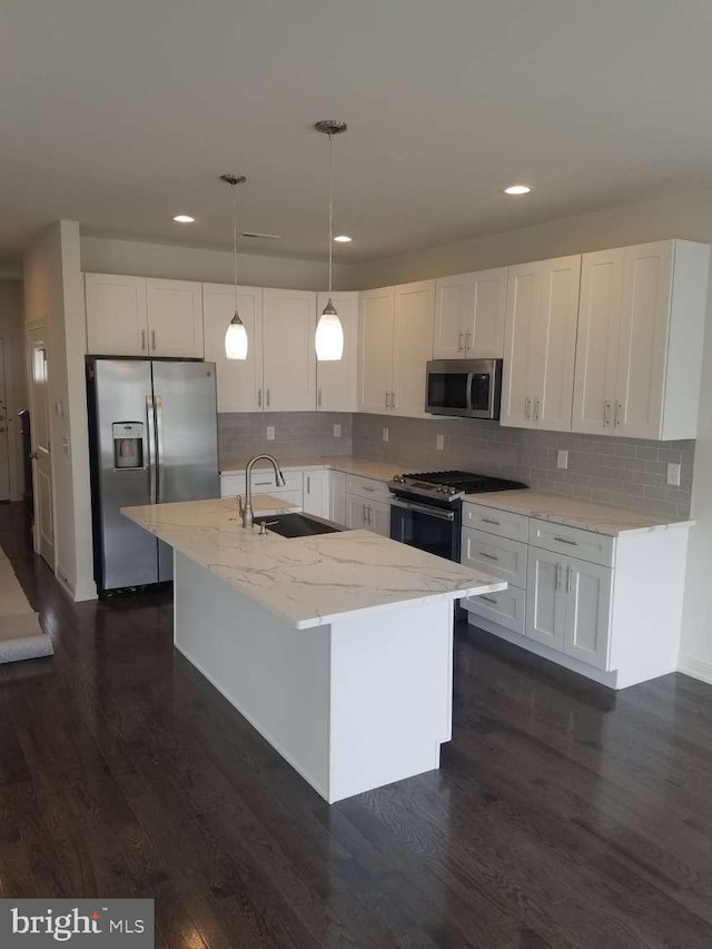 kitchen with a center island with sink, pendant lighting, sink, stainless steel appliances, and white cabinets