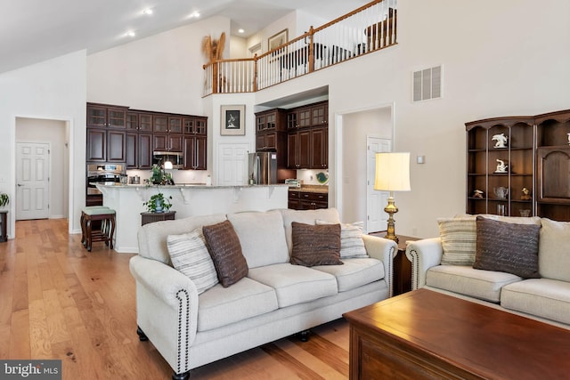 living room with high vaulted ceiling and light wood-type flooring