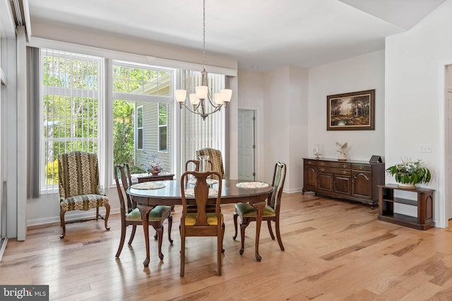 dining space with light hardwood / wood-style floors and a notable chandelier