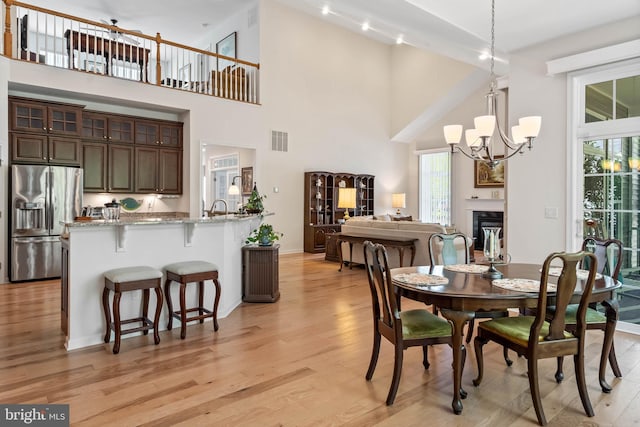 dining space featuring a high ceiling, a notable chandelier, and light wood-type flooring