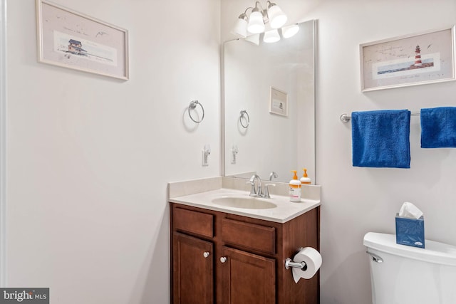 bathroom featuring vanity, a chandelier, and toilet