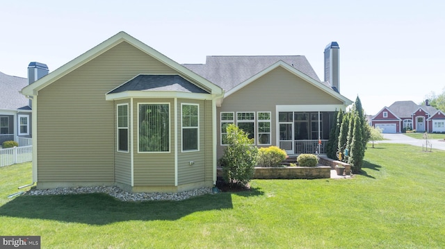 rear view of house with a yard and a sunroom