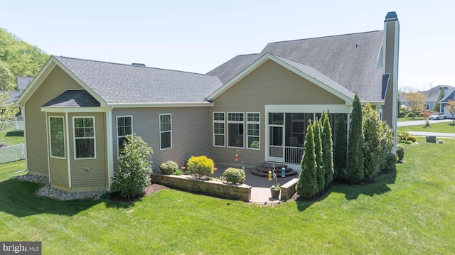 rear view of house with a yard, a sunroom, and a patio area