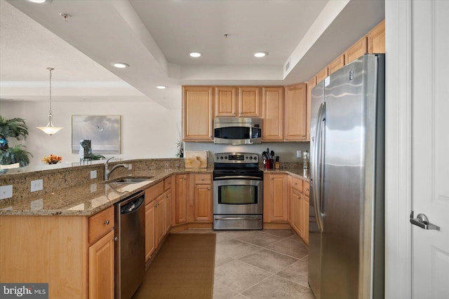 kitchen with kitchen peninsula, appliances with stainless steel finishes, a tray ceiling, light stone counters, and sink