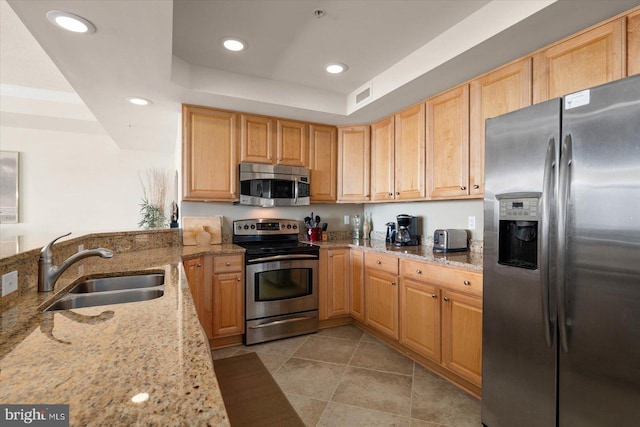 kitchen featuring light stone countertops, stainless steel appliances, sink, light tile floors, and a raised ceiling