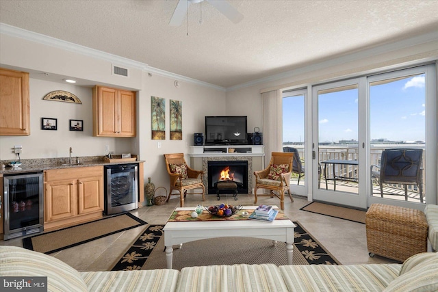 tiled living room featuring sink, crown molding, a textured ceiling, and beverage cooler