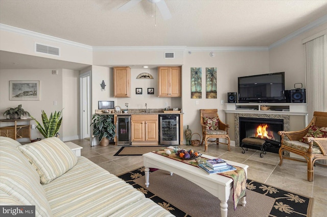 living room with beverage cooler, ceiling fan, crown molding, and light tile floors