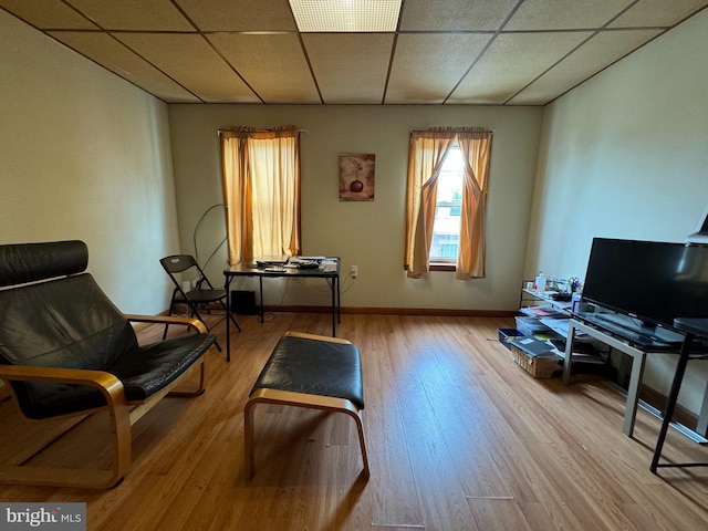 sitting room with a drop ceiling and wood-type flooring