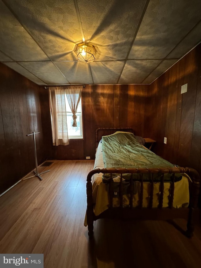 bedroom featuring hardwood / wood-style flooring and wooden walls