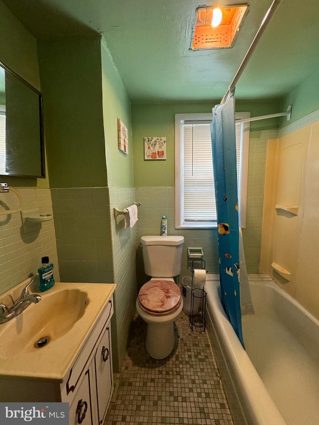 full bathroom featuring vanity with extensive cabinet space, shower / bath combo with shower curtain, tile walls, tile flooring, and toilet