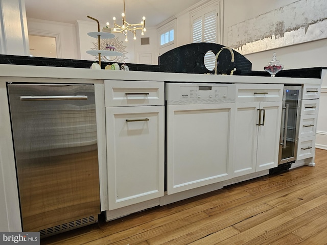 kitchen with white cabinets, a notable chandelier, and light wood-type flooring