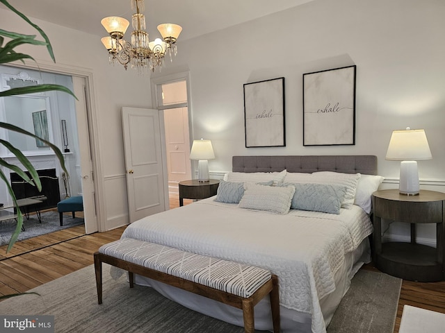 bedroom with an inviting chandelier and hardwood / wood-style floors